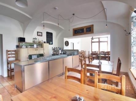 Prostorná jídelna s dlažbou a dřevěným nábytkem, velká okna poskytují dostatek světla, moderní barový pult z nerezové oceli. | Prodej - hotel, 350 m²