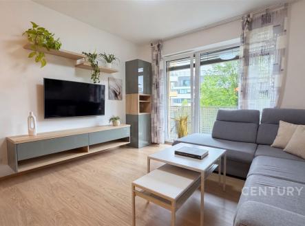 Světlý obývací pokoj s dřevěnou podlahou, velkými okny a moderním nábytkem. | Prodej bytu, 2+kk, 62 m²