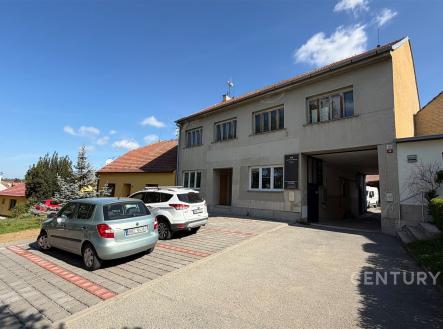Na dvoře rodinného domu se nachází parkovací prostor s dlažbou a zpevněným povrchem, vedlejší zahrada a světlá fasáda budovy. | Pronájem - skladovací prostor, 103 m²