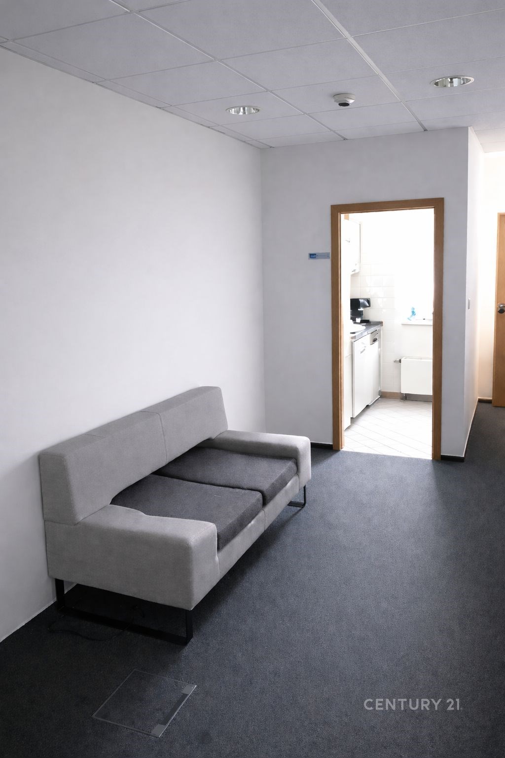 Šedá chodba s kobercem, moderní sedačka, vstup do světlé kuchyně s dlažbou, minimalismus, rekonstruovaný prostor v bytě