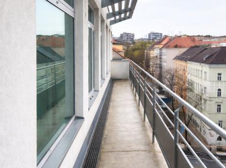 Úzký balkon s betonovou podlahou, moderní zábradlí a velká okna, nabízí výhled na městské panorama, ideální pro kompaktni bydlení v centru města. | Pronájem - kanceláře, 350 m²