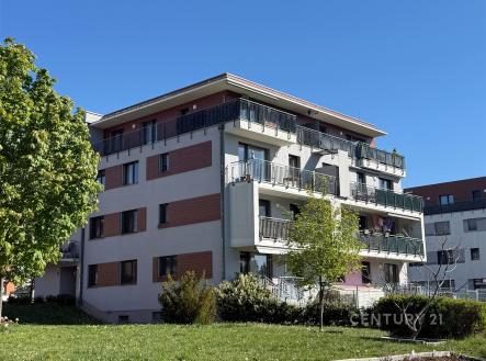 Exteriér moderního bytového domu s rozsáhlými balkony, parkovou zelení a světlou fasádou v klidné čtvrti. | Pronájem bytu, 3+kk, 77 m²