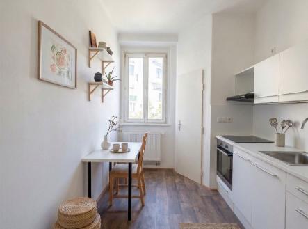 Kompaktní kuchyň s moderními spotřebiči, dřevěnou podlahou a světlými skříňkami, velké okno poskytuje dostatek přirozeného světla. | Pronájem bytu, 3+1, 84 m²