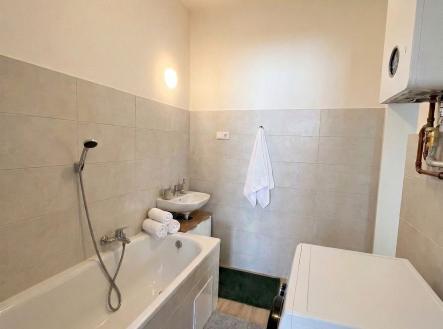 Koupelna s moderní dlažbou a světlými obklady, vybavená vanou, umyvadlem a pračkou. | Pronájem bytu, 3+1, 84 m²
