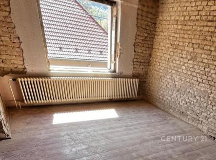 Pokoj ve fázi rekonstrukce s odkrytými cihlovými stěnami, světlým dřevěným podlahovým povrchem a velkým oknem pro přirozené světlo. | Prodej - dům/vila, 350 m²