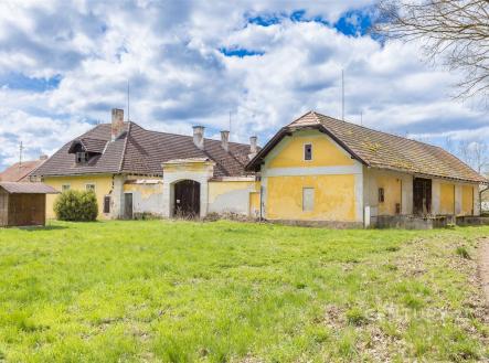 Historický exteriér venkovského stavení s žlutou fasádou, šikmou střechou a rozsáhlým travnatým pozemkem, vhodný pro rekonstrukci. | Prodej - zemědělský objekt, 15 909 m²