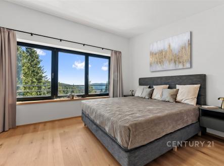 Prostorná ložnice s parketovou podlahou nabízí velká okna s výhledem na krajinu, v moderním stylu s neutrálními tóny a elegantní výzdobou. | Prodej bytu, 3+kk, 68 m²
