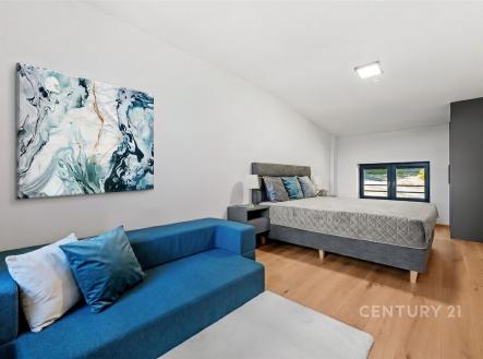 Prostorná ložnice s dřevěnou podlahou, velkými okny a moderním nábytkem, poskytující světlý a komfortní prostor pro relaxaci. | Prodej bytu, 4+kk, 102 m²