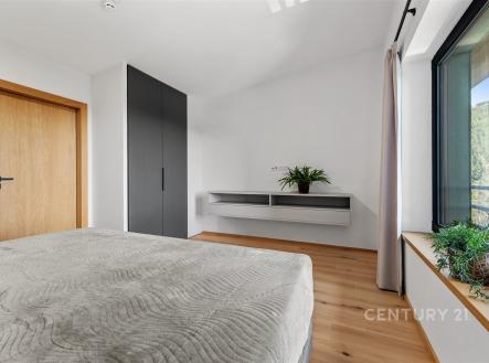 Prostorná ložnice s parketovou podlahou, velká okna nabízejí výhled, moderní vestavěné skříně a minimalistický design vytvářejí světlý prostor. | Prodej bytu, 4+kk, 102 m²