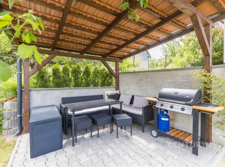 Zahradní terasa s pergolou, moderní dlažbou a zahradním nábytkem, ideální pro relaxaci a grilování, součástí je i plynový gril | Prodej - dům/vila, 117 m²