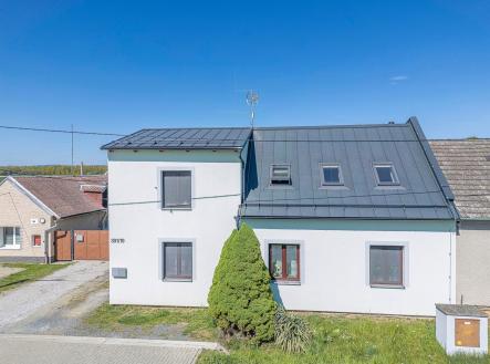 Renovovaná fasáda rodinného domu s moderní střechou, střešními okny a udržovanou zahradou na klidné ulici v malebném venkovském prostředí. | Prodej - dům/vila, 210 m²