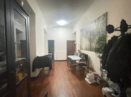 Dlouhá úzká jídelna s dřevěnou podlahou, moderní výzdobou a vestavěnou skříní, vytváří praktický a útulný prostor pro stolování. | Pronájem bytu, garsoniéra, 13 m²