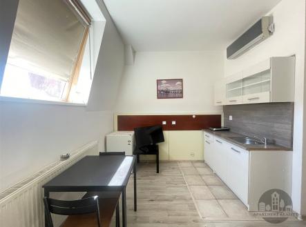 Kuchyňský kout s dlažbou a parketovou podlahou, moderní bílá linka a velké střešní okno pro dostatek světla | Pronájem bytu, 1+kk, 24 m²