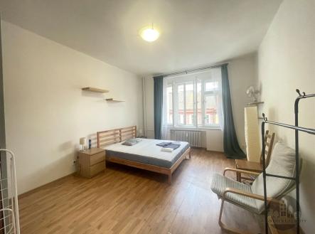 Světlá ložnice s parketovou podlahou, velká okna, moderní nábytek a minimalistický styl. | Pronájem bytu, 2+kk, 40 m²