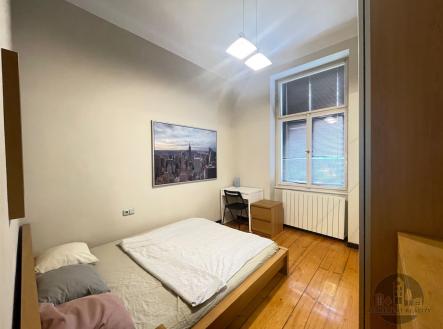Prostorná ložnice s dřevěnou podlahou, velkým oknem a moderním nábytkem nabízí světlou a útulnou atmosféru. | Pronájem bytu, garsoniéra, 13 m²