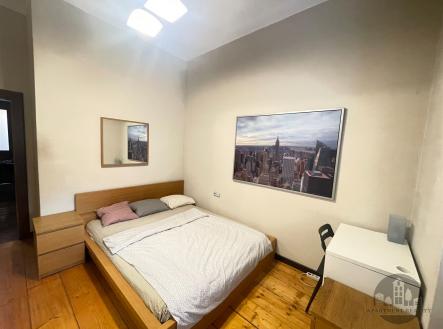 Světlá ložnice s dřevěnou podlahou a moderním nábytkem, velký obraz na stěně, světlé stěny, příjemná atmosféra pro pohodlné bydlení. | Pronájem bytu, garsoniéra, 13 m²
