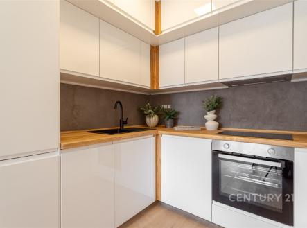 Moderní kuchyň, světlé skříňky s dřevěnou pracovní deskou, elegantní černá armatura, vestavěná trouba, minimalistický design | Prodej bytu, 2+kk, 42 m²