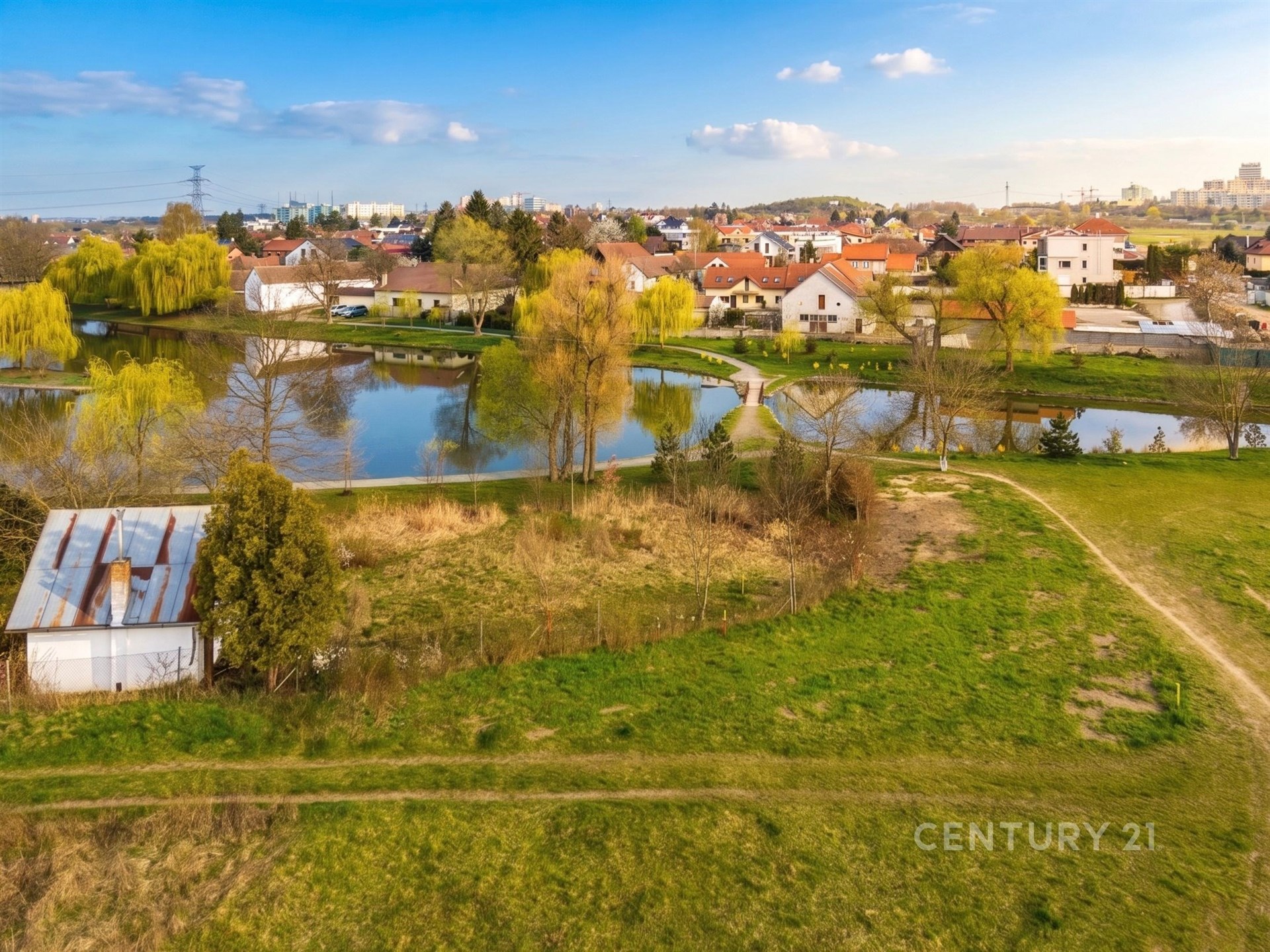 Jezero s okolní přírodou a vilovou čtvrtí, větve vrb a klidná lokalita.