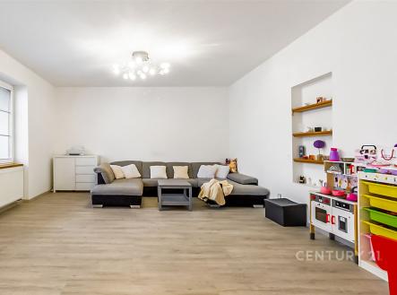 Světlý obývací pokoj s moderní parketovou podlahou, velká okna poskytují přirozené světlo, minimalistický styl s vestavěnými policemi | Prodej - dům/vila, 410 m²