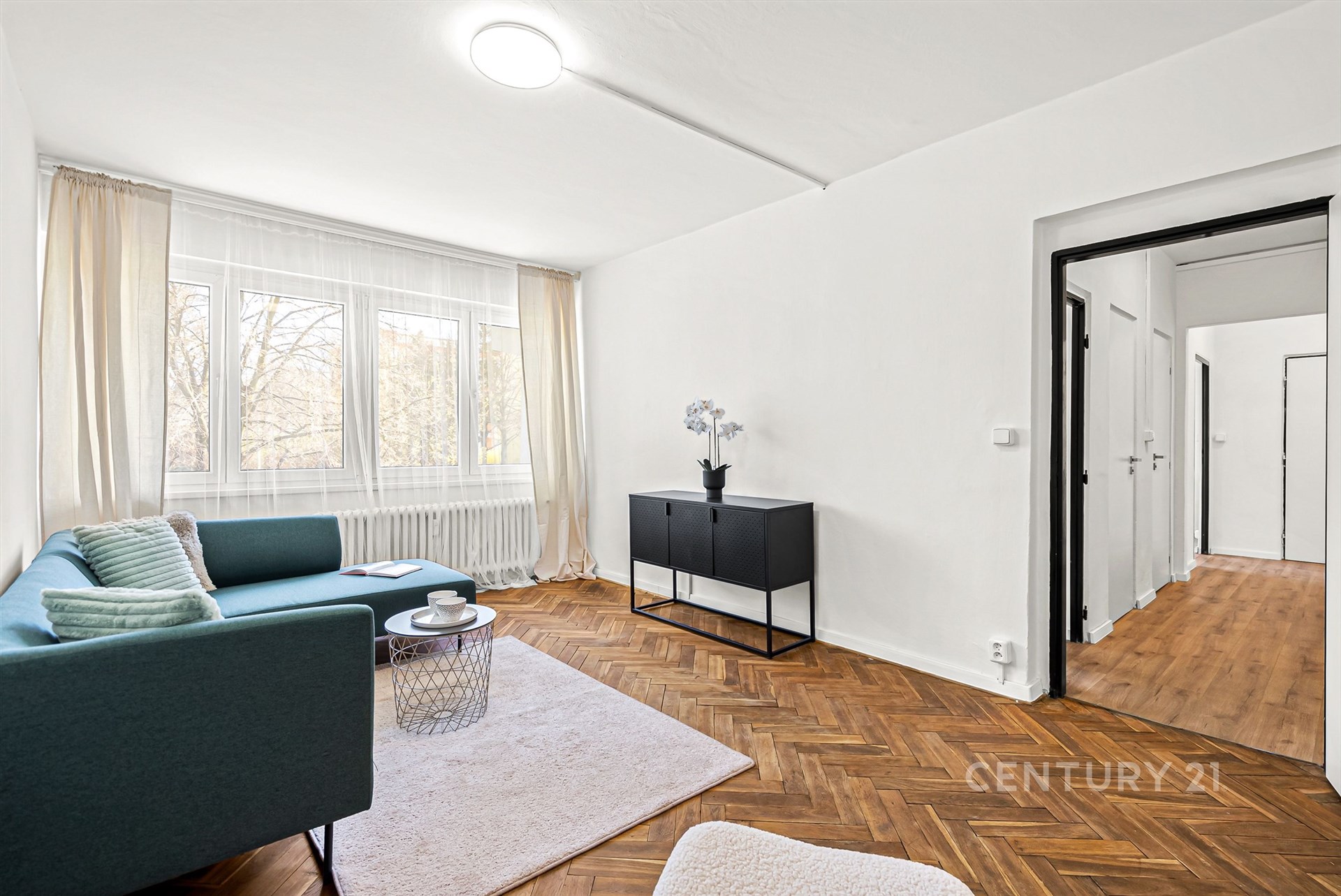 Světlý obývací pokoj s parketovou podlahou, velká okna, moderní vybavení, útulný interiér s elegantním nábytkem a výhledem do zahrady.