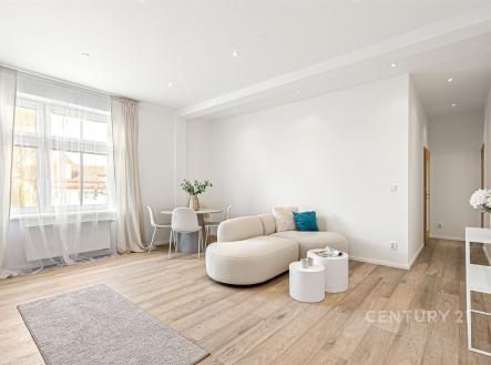 Světlý obývací pokoj s moderním designem, parketová podlaha a velká okna, které zajišťují dostatek přirozeného světla, nabízí komfortní bydlení. | Prodej bytu, 2+kk, 61 m²