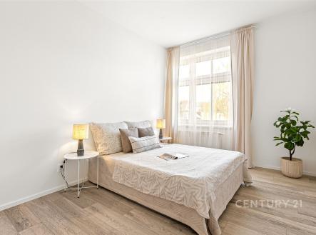 Světlá ložnice s dřevěnou podlahou, velkým oknem a moderním designem nabízí příjemné a útulné prostředí pro relaxaci. | Prodej bytu, 2+kk, 61 m²