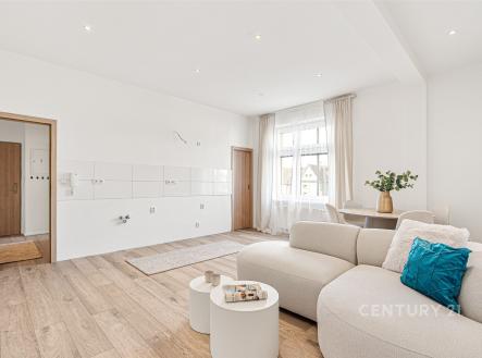 Světlý obývací pokoj s parketovou podlahou, velkými okny a moderním nábytkem. Prostor nabízí rekonstrukci a otevřený koncept s přírodním osvětlením. | Prodej bytu, 2+kk, 61 m²