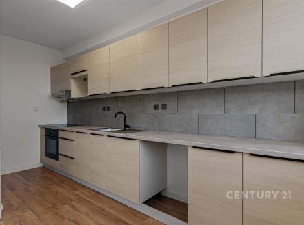 Moderní kuchyň s parketovou podlahou, světlými dřevěnými skříňkami a elektrickou troubou, šedá dlažba na stěně dodává elegantní vzhled. | Pronájem bytu, 3+kk, 90 m²