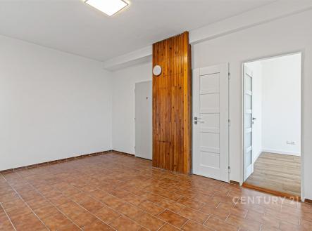 Prázdný obývací pokoj s dlažbou a dřevěným obkladem, vedoucí do moderního interiéru, světlý prostor s bílými dveřmi, připraven k transformaci | Pronájem bytu, 3+kk, 90 m²