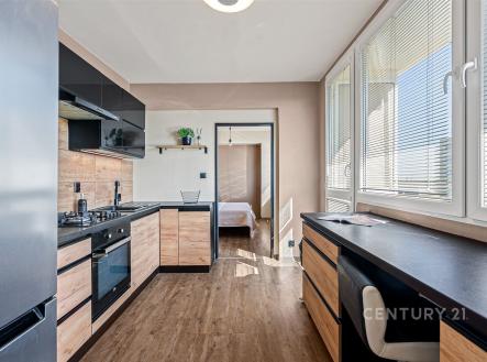 Moderní kuchyň s dřevěnými prvky a vestavěnými spotřebiči, světlá díky velkým oknům. Parketová podlaha a elegantní design přináší útulnost. | Prodej bytu, 3+1, 70 m²