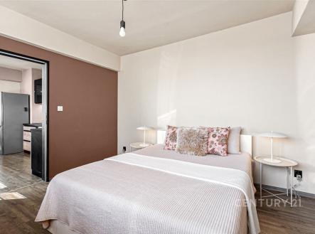 Prostorná ložnice s dřevěnou podlahou, moderními lampami a světlými stěnami, doplněná velkou postelí se stylovými polštáři. | Prodej bytu, 3+1, 70 m²