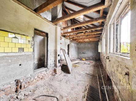 Rekonstrukce interiéru s odkrytými dřevěnými trámy, cihlovou zdí a velkými okny. Potenciál pro moderní přeměnu prostoru. | Prodej - dům/vila, 112 m²