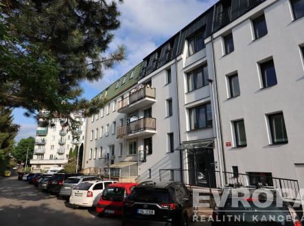 Moderní bytový dům, rekonstruovaný exteriér, bílá fasáda, velká okna, klidná rezidenční ulice, parkování před budovou. | Pronájem bytu, 2+kk, 47 m²