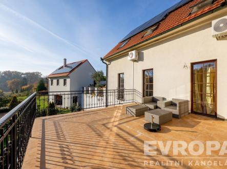 Prostorná terasa s dlažbou, elegantním zábradlím a výhledem na zahradu, ideální pro relaxaci, vybavená moderním nábytkem a venkovní klimatizací. | Prodej - dům/vila, 350 m²