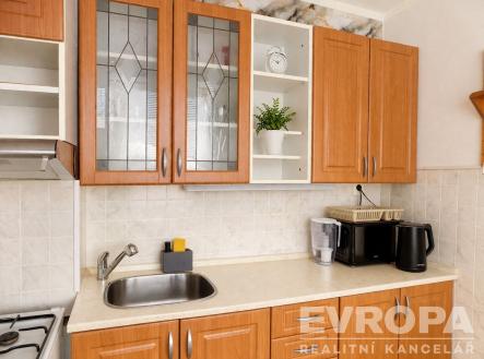 Moderní kuchyň s dřevěnými skříňkami, bílou dlažbou a vestavěnými spotřebiči, poskytuje světlý a praktický prostor pro vaření. | Prodej bytu, 2+1, 53 m²