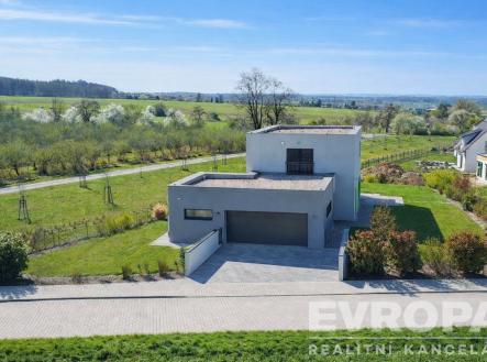 Moderní rodinný dům s plochou střechou a garáží, obklopený udržovanou zahradou, dlážděná příjezdová cesta, klidná lokalita blízko přírody. | Prodej - dům/vila, 229 m²