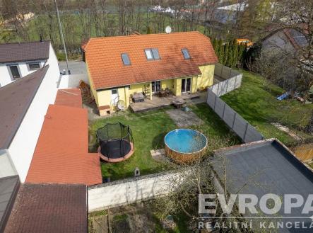 Zahrada s rodinným domem, terasou a bazénem. Zahrada nabízí trávník, dřevěné doplňky a trampolínu, ideální pro relaxaci a rodinný život. | Prodej - dům/vila, 213 m²