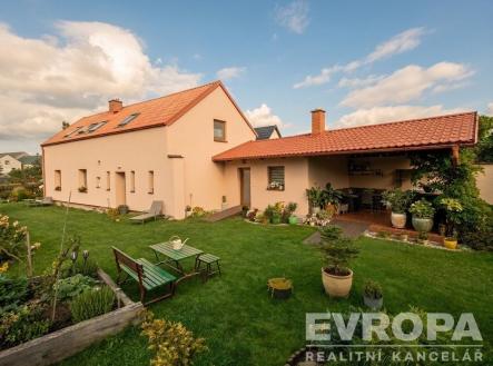 Zahrada u rodinného domu s pečlivě udržovaným trávníkem, zahradní nábytek a pergola. Střecha domu s červenou taškou, klidné okolí. | Prodej - dům/vila, 180 m²