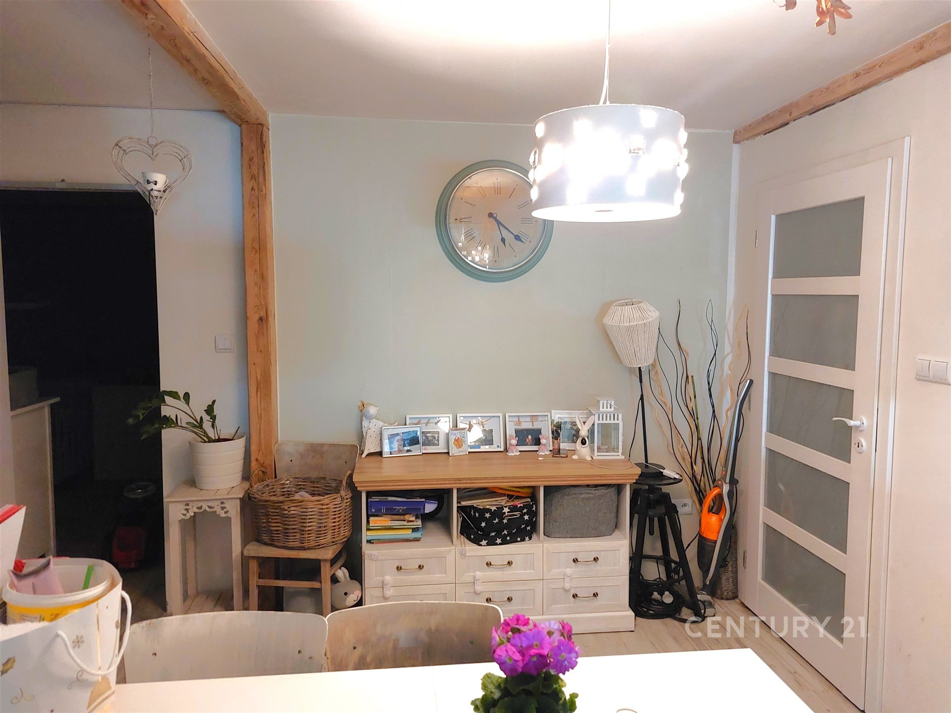 Jídelní kout s moderním osvětlením, světlými stěnami a dřevěnými akcenty, doplněný vkusnou dekorací a praktickými úložnými prostory.