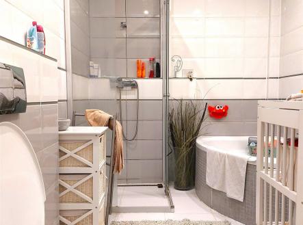 Moderní koupelna s dlažbou a sprchovým koutem, nabízí světlé stěny a praktické úložné prostory. | Prodej - dům/vila, 119 m²