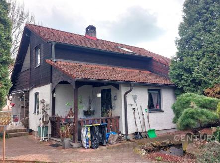 Rodinný dům se šikmou střechou a cihlovými taškami, obložený dřevem. Prostorná zahrada s chodníkem a okrasnými stromy. | Prodej - dům/vila, 119 m²