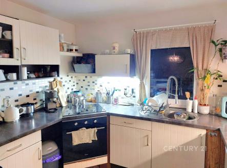 Moderní kuchyň s dlažbou a vestavěnými spotřebiči. Velká okna s elegantními závěsy zajišťují světlost prostoru. | Prodej - dům/vila, 119 m²