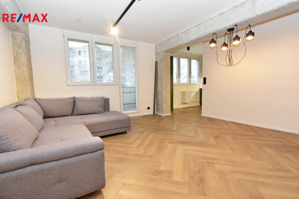 Obývací pokoj s kuchyňským koutem a vstupem na balkón.