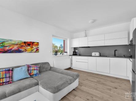 Moderní kuchyň s bílou vestavěnou linkou, parketovou podlahou a velkým oknem, které osvětluje prostor. | Prodej bytu, 3+kk, 135 m²