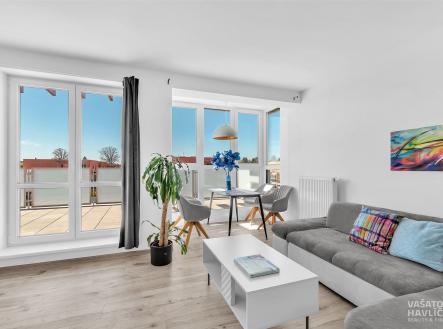 Světlý obývací pokoj s moderní parketovou podlahou, velkými okny a elegantním nábytkem, poskytuje přístup na prostorný balkon | Prodej bytu, 3+kk, 135 m²