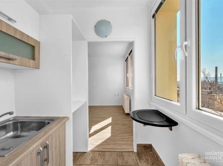 Kuchyňský kout s dlažbou, dřevěnými skříňkami a moderním designem, vedoucí do světlého pokoje s velkými okny a parketovou podlahou. | Pronájem bytu, 1+kk, 26 m²