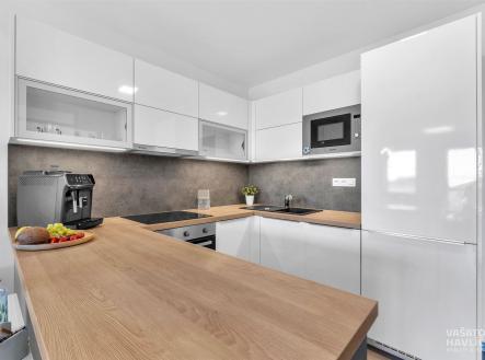Moderní kuchyň s dřevěnou pracovní deskou, bílými skříněmi a vestavěnými spotřebiči. Světlý prostor s elegantním designem a praktickým uspořádáním. | Pronájem bytu, 3+kk, 103 m²