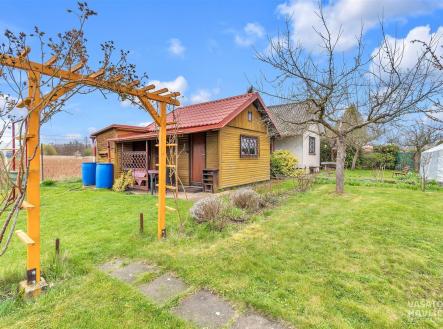Zahradní domek na rozlehlém pozemku s udržovaným trávníkem, dřevěnými prvky a ovocnými stromy, ideální pro rekreační využití. | Prodej - chata/rekreační objekt, 32 m²