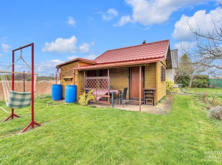 Malá chatka s dřevěnou fasádou, okolní zahrada s trávníkem a venkovním posezením, klidné prostředí na okraji vesnice. | Prodej - chata/rekreační objekt, 32 m²