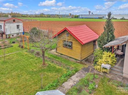 Zahrada s chatkou a terasou, obklopená zelení a záhony. Dřevěná stavba s červenou střechou, vhodná pro rekreaci a relaxaci. | Prodej - chata/rekreační objekt, 32 m²